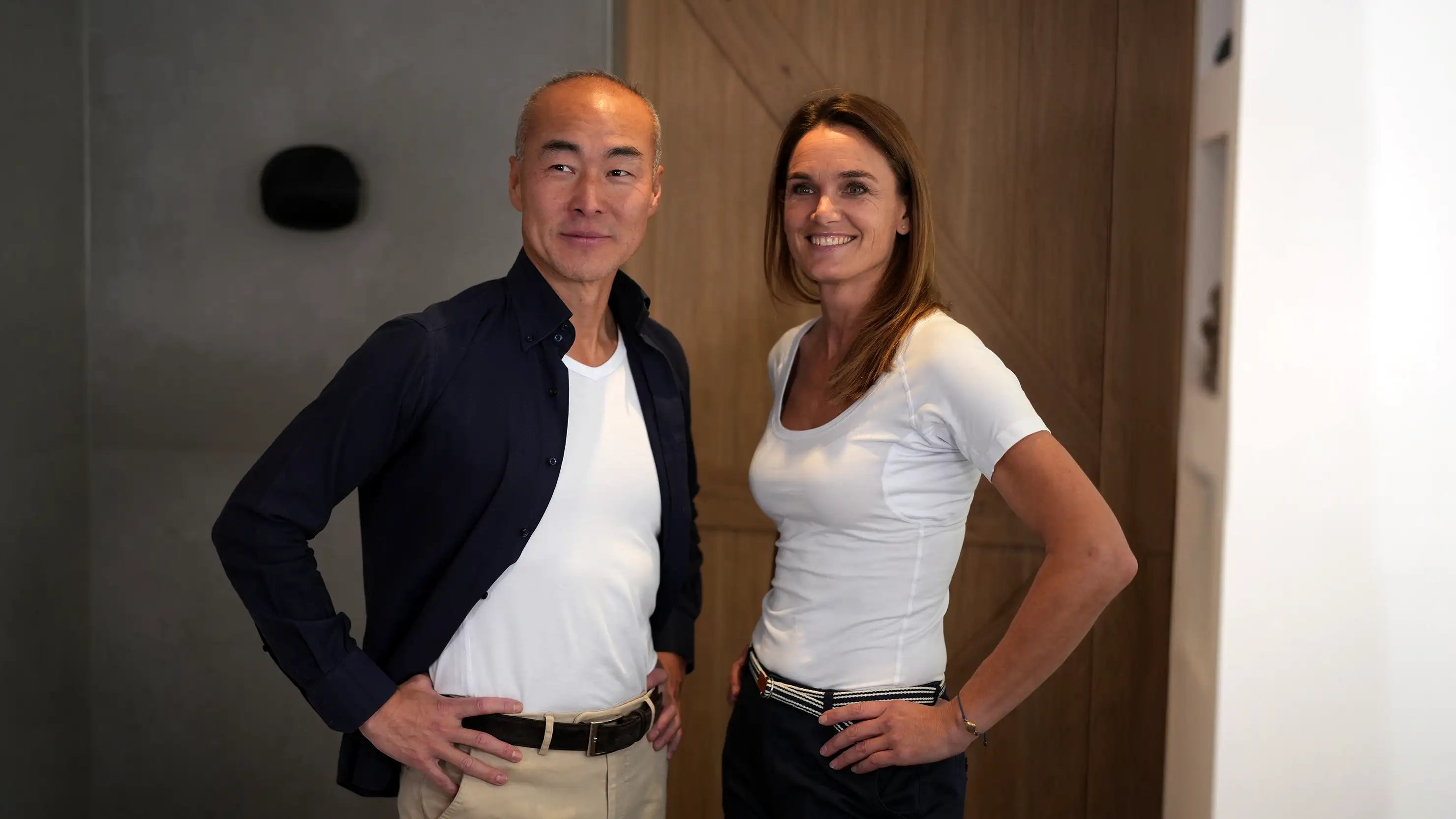 Man and woman scene photo standing in a bathroom with cheerful confident expressions, wearing white ConfidenceForAll shirts