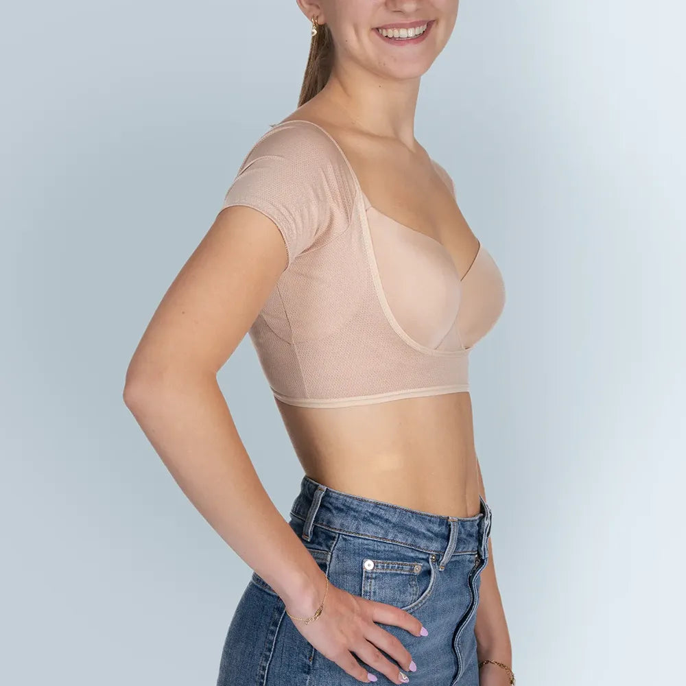 Vrouw model met BEIGE ANTI ZWEET COLLEGE TOP van ConfidenceForAll en blauwe spijkerbroek zij aanzicht in studio