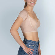 Vrouw model met BEIGE ANTI ZWEET COLLEGE TOP van ConfidenceForAll en blauwe spijkerbroek zij aanzicht in studio