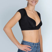 Vrouw model met zwarte ANTI ZWEET COLLEGE TOP van ConfidenceForAll en blauwe spijkerbroek schuin vooraanzicht in studio met lichtblauwe achtergrond