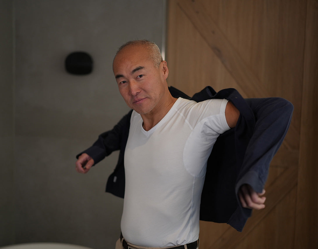 Scenefoto af mand, der tager en blå skjorte på over en hvid ConfidenceForAll anti-sved shirt