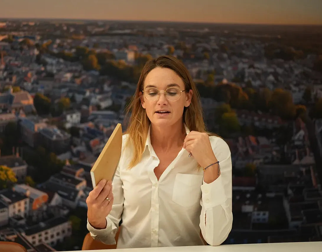 Scenefoto af kvinde med hvid bluse, der har det varmt og vifter med en notesblok