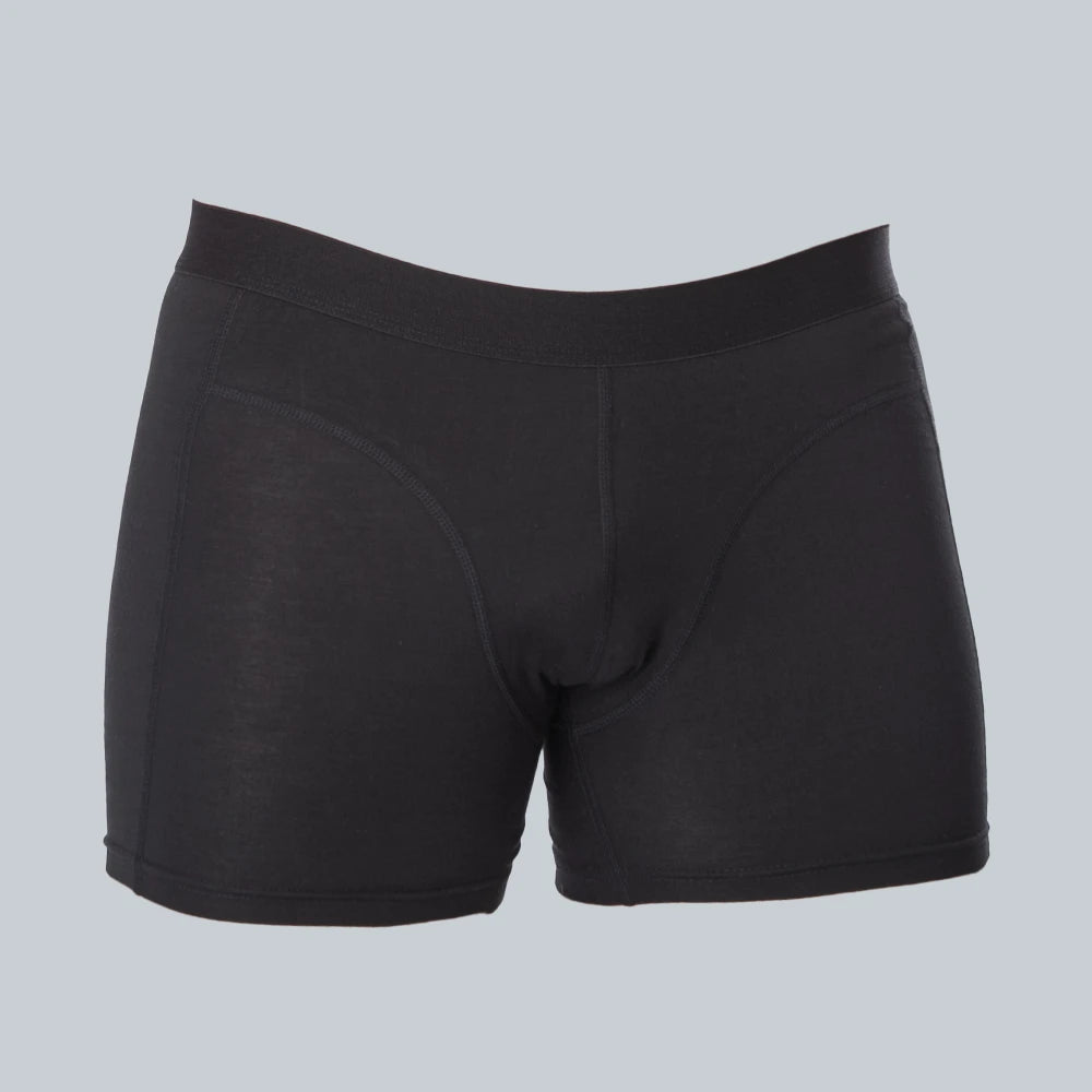 3D-studiofotografie van de voorkant van een zwarte, anti-transpirant, zweetbestendige boxershort van ConfidenceForAll met zweetpads op een effen grijsblauwe achtergrond.