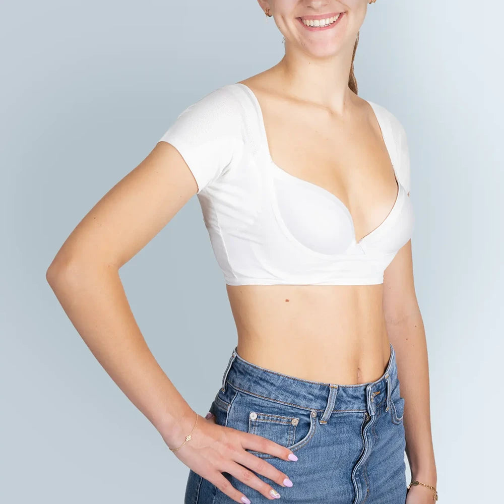 Vrouw model met witte ANTI ZWEET COLLEGE TOP van ConfidenceForAll en blauwe spijkerbroek schuin vooraanzicht in studio