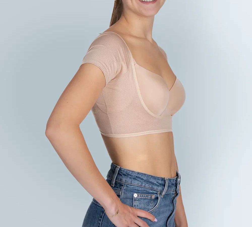 Vrouw model met BEIGE ANTI ZWEET COLLEGE TOP van ConfidenceForAll en blauwe spijkerbroek zij aanzicht in studio  