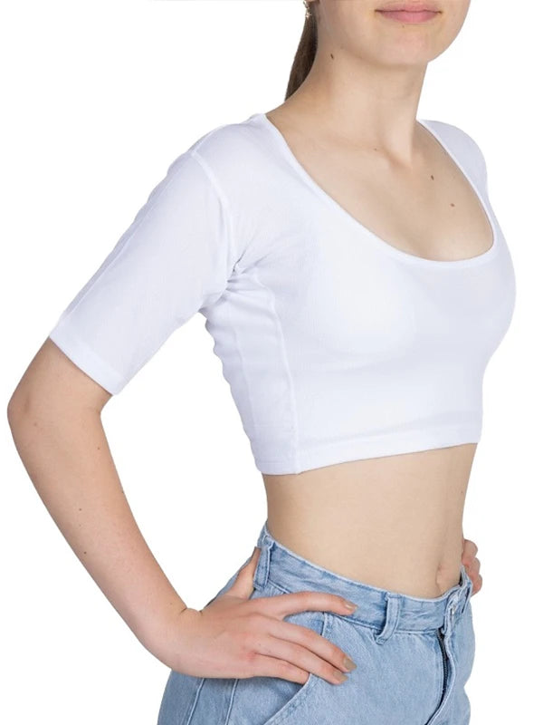 Een meisje draagt ​​een witte ConfidenceForAll antizweet crop top met halflange mouwen en een lichtblauwe spijkerbroek. Ze staat met haar handen in haar zij tegen een witte achtergrond.
