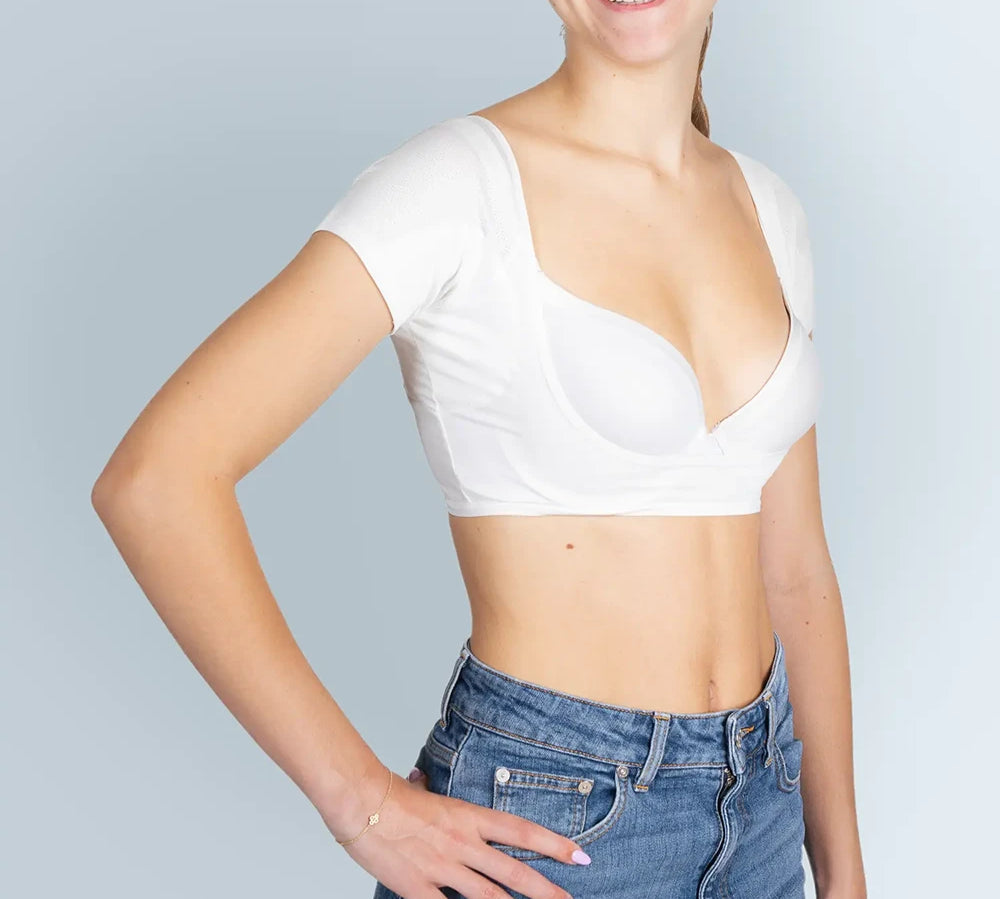 Vrouw model met witte ANTI ZWEET COLLEGE TOP van ConfidenceForAll en blauwe spijkerbroek schuin vooraanzicht in studio  